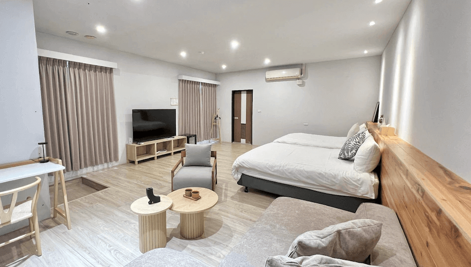 【水里住宿】水里里山村德川森態旅館寬敞現代的客房，設有兩張大床，搭配木質桌椅與舒適的沙發，風格簡約溫馨，提供舒適的住宿空間。房間內的電視與窗簾增添了居家感，適合家庭或朋友入住。