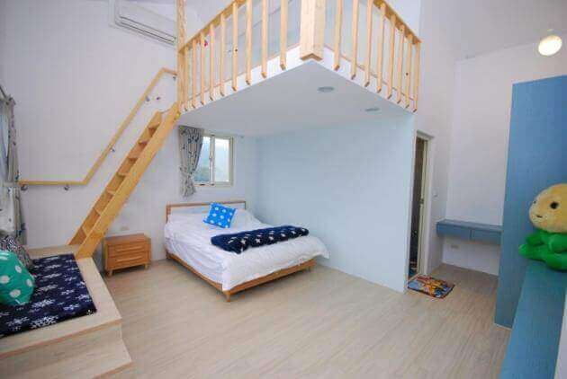 【大湖住宿】水頭人家生態美學民宿的雙層結構房間，牆面為淺藍色調，一樓有一張雙人床，周圍設有木質家具與窗戶，光線明亮，空間佈局簡約且實用。