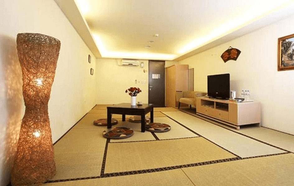 【烏來住宿】泉世界溫泉會館的日式榻榻米房型，內部空間寬敞，中央擺放一張矮桌與座墊，牆角裝飾有竹編燈，整體設計溫暖且舒適，適合家庭聚會或團體入住。