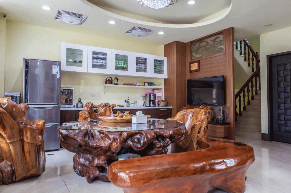 【溪頭住宿】溪頭新景宏渡假村民宿的公共空間設有原木雕刻家具與圓形餐桌，散發出濃厚的自然氣息，結合現代化廚房設備，提供旅客舒適的交流與用餐環境，非常適合家庭聚會或團體旅遊。