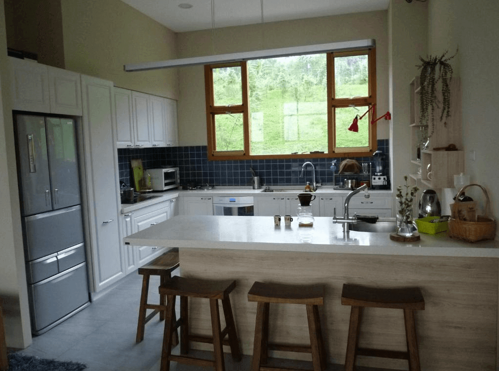 【溪頭住宿】溪頭有晴天民宿的廚房設計開放且實用，以白色櫥櫃搭配深色瓷磚，提供完整的烹飪設備，窗外能看到綠意盎然的自然景觀，是旅客自炊的理想場地。