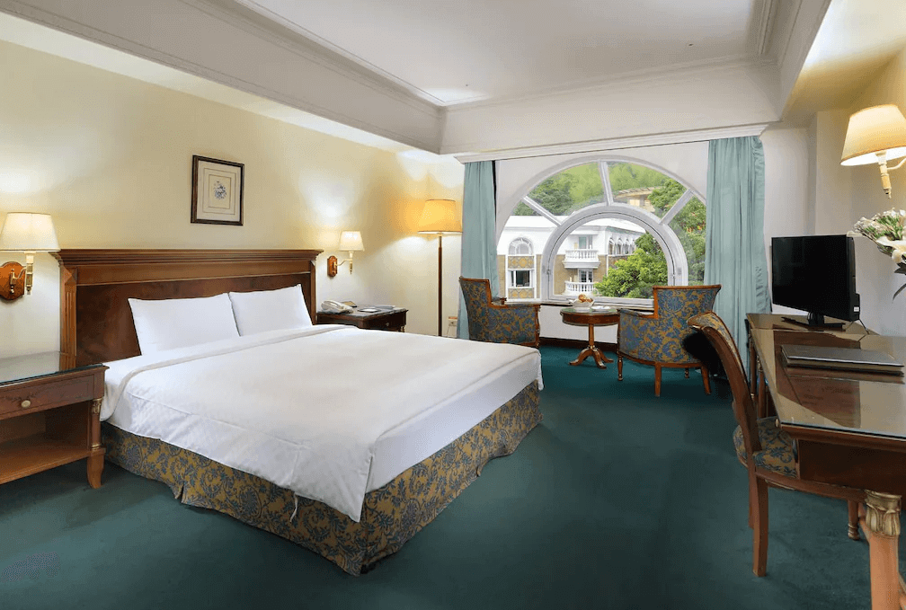 【溪頭住宿】溪頭米堤大飯店的一間優雅的客房，採用歐式古典風格設計，配有大型窗戶、圓形鏡面裝飾以及木質家具，提供舒適的休憩環境。