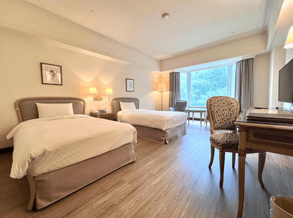 【溪頭住宿】溪頭米堤大飯店的兩張雙人床的溫馨客房，簡約的布置與柔和燈光營造出溫暖的氛圍，窗外綠意盎然。