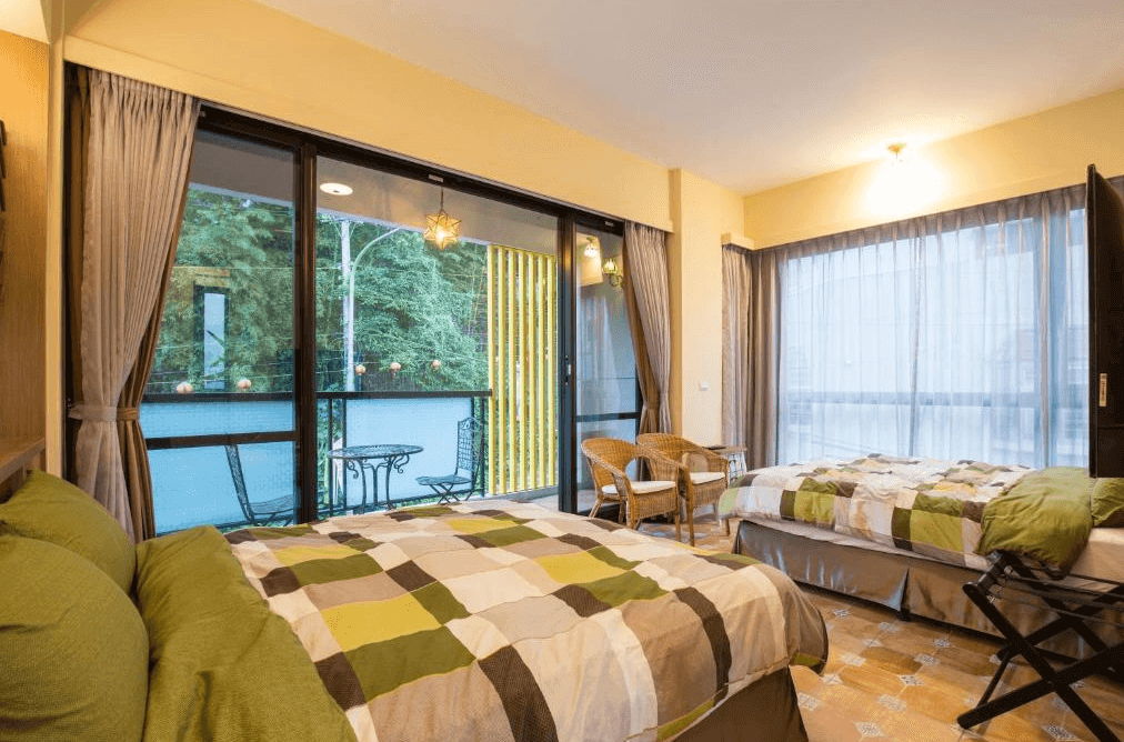 【溪頭住宿】漫步山嵐的房間設計以柔和的色彩與窗外綠意結合，兩張大床搭配舒適的寢具與座椅，還有陽台提供室外放鬆空間，適合家庭或朋友同遊，享受大自然的寧靜。