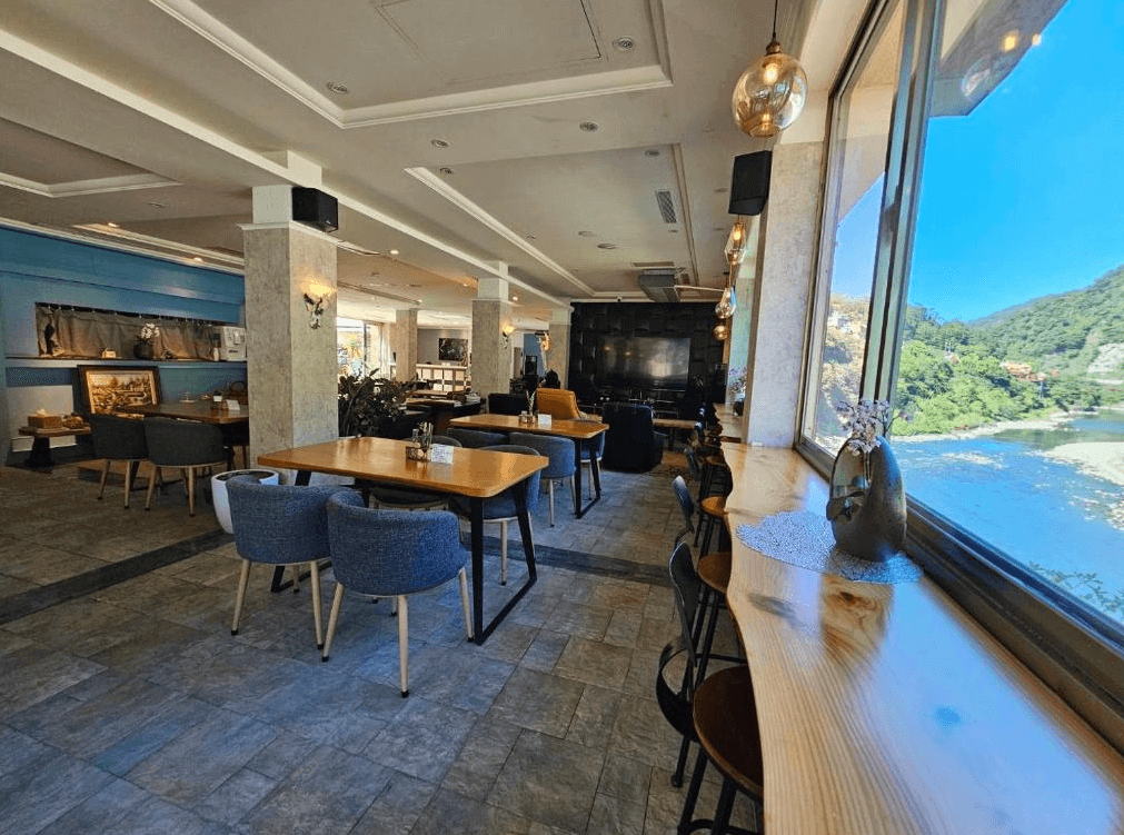 【烏來住宿】烏來水岸溫泉餐廳內有多種座位選擇，落地窗外可見山河美景，桌椅設計簡約舒適，空間採用大理石地板與柔和燈光點綴，適合用餐與聚會的場所。