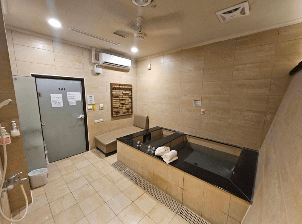 【烏來住宿】烏來水岸溫泉的溫泉池，周圍為淺色瓷磚牆壁，配備乾濕分離的淋浴區及休息座椅，提供私密且放鬆的泡湯體驗，整體設計簡約大方。