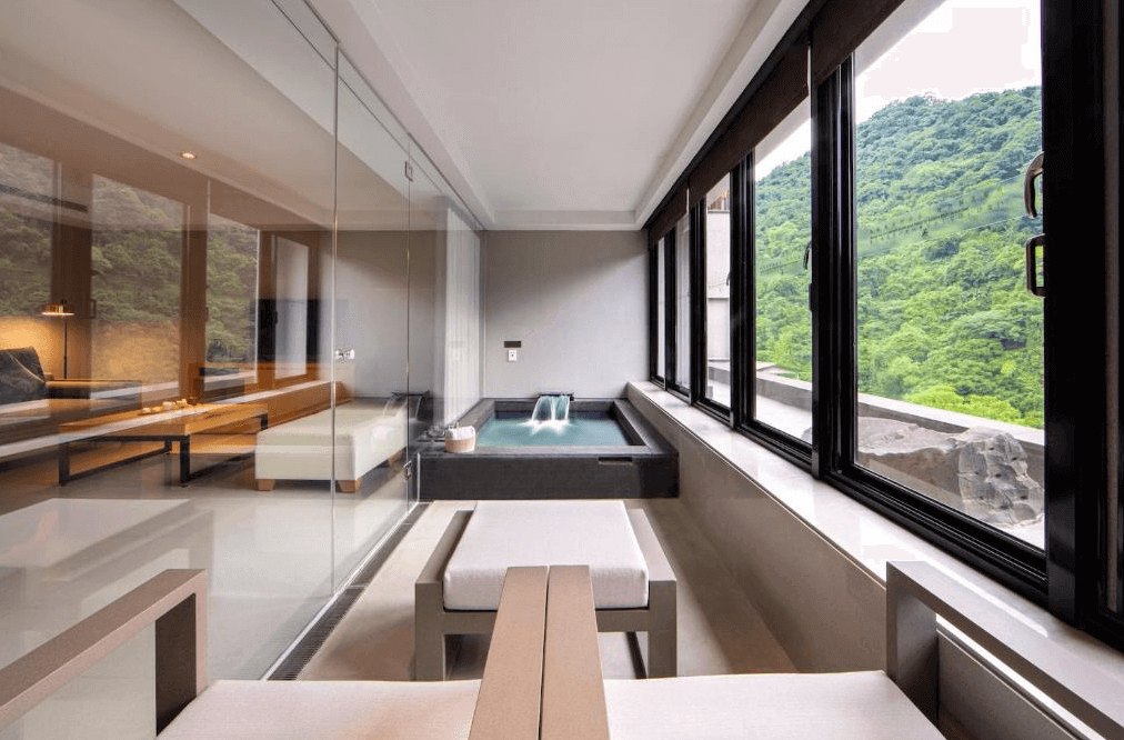 【烏來住宿】璞石麗緻溫泉會館的私人溫泉區採用大面玻璃窗設計，可直接欣賞窗外山林美景。黑色石材溫泉池與休憩區緊密相連，設計簡潔大方，提供極佳的私密性與舒適感。