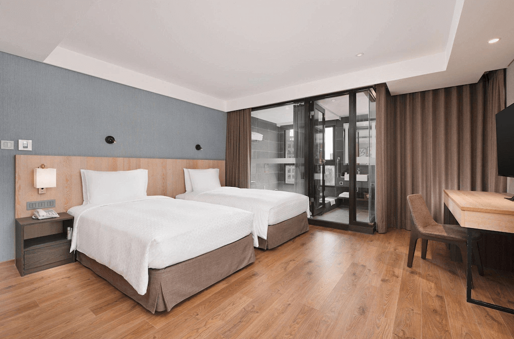 【礁溪住宿】礁溪福朋喜來登酒店的雙床房，內部設計簡潔，木質地板與淺灰色牆壁搭配和諧，落地窗外連接寬敞的浴室，浴室內配備了現代化的泡湯設施，非常適合家庭或朋友入住。