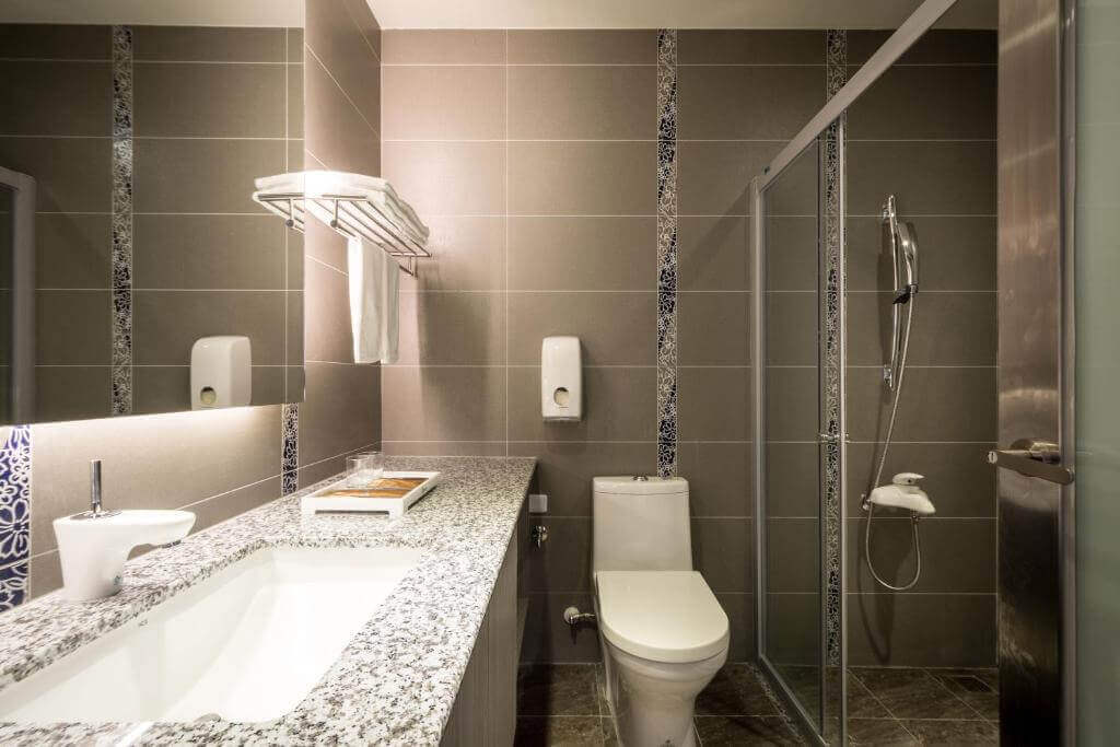 【北港住宿】禾都商務飯店的浴室設計以深灰色磁磚為主，搭配花紋點綴，乾濕分離淋浴間與大理石洗手台相輔，提供整潔且高質感的使用體驗。