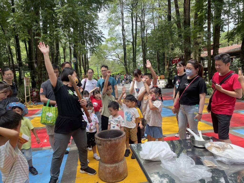 【美濃住宿】美濃德旺山莊的戶外活動場景，一群家庭和孩子們參與趣味活動。場地周圍被高大的綠樹環抱，活動氣氛熱鬧，適合親子共同參與的娛樂項目。