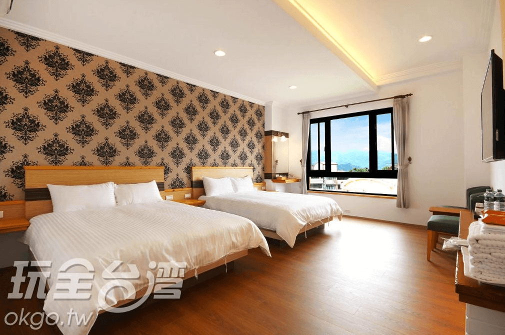 【溪頭住宿】荳田町家庭入住的雙床房，兩張大床搭配牆面的典雅花紋壁紙，整體空間充滿溫馨感，窗外的景緻增添住宿體驗的愉悅感。
