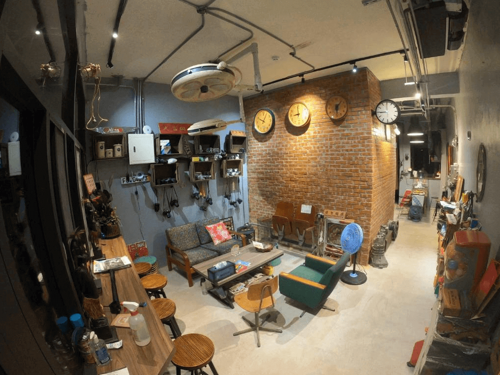 【玉里住宿】途中玉里青年旅舍的公共空間，擺放著多樣化的復古傢俱與裝飾品，如牆上的老式時鐘和架子上的擺設，並提供多功能座椅和長桌，方便住客交流或休憩。