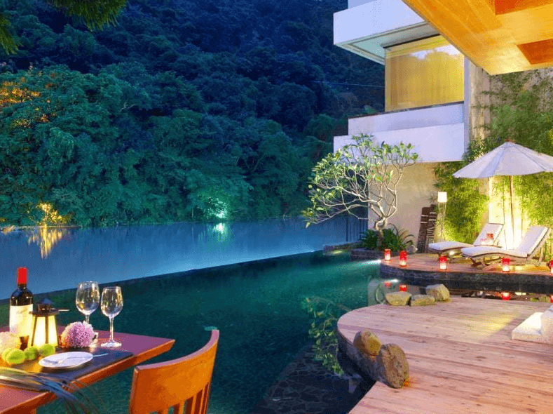 【烏來住宿】馥蘭朵烏來渡假酒店的戶外泳池區於夜晚燈光襯托下更顯浪漫，池邊設有餐桌椅和日光浴床，周圍環繞自然景觀，適合享受寧靜的度假時光。