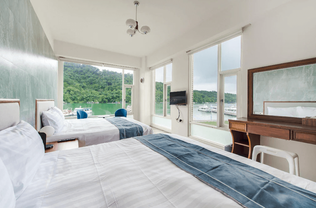 【日月潭住宿】H& 日月潭水漾的房間內設有兩張大床，窗外可見日月潭美景，採光良好，設計簡約優雅，床上鋪設清爽的白色床單，營造舒適的入住氛圍。