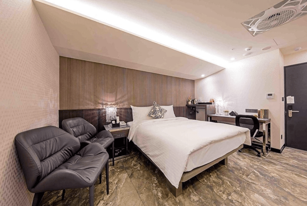 【寧夏夜市住宿】Hotel I Journey 愛行旅的大床房，搭配舒適的皮質座椅與書桌，房間採用木質牆面設計，地板為大理石風格，整體氛圍溫馨且高雅。