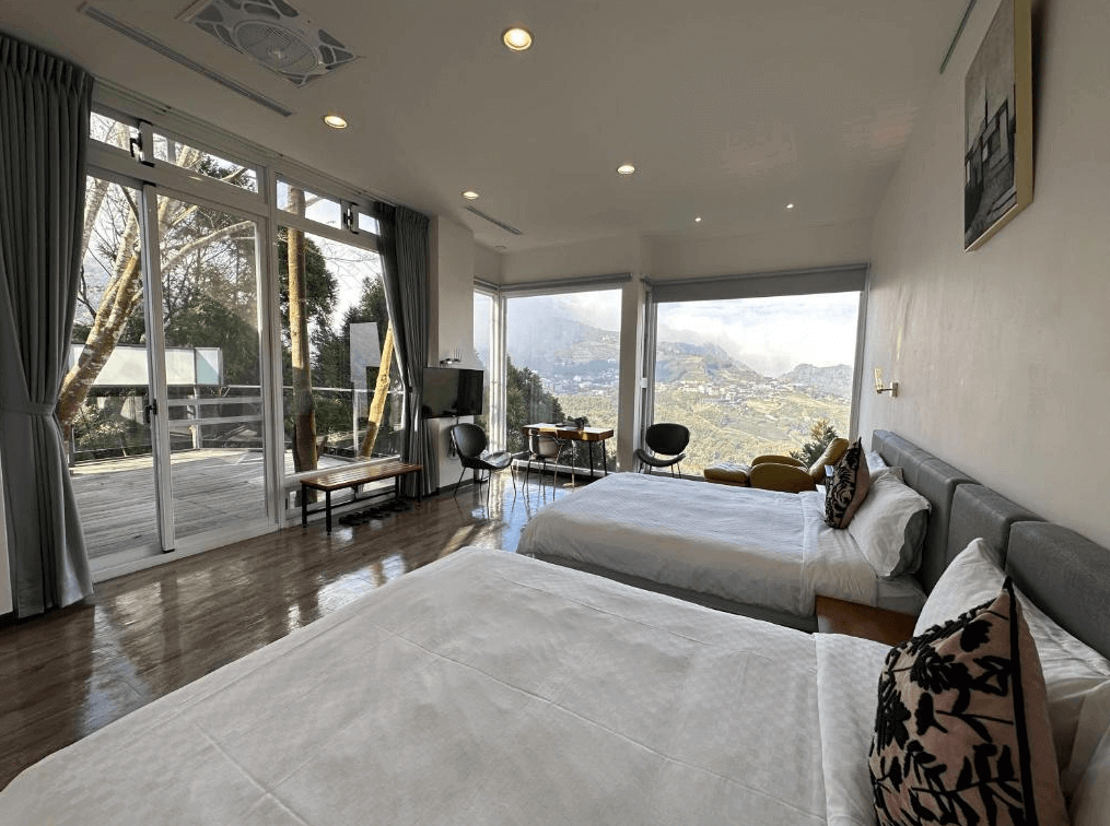 【阿里山住宿】十方山水的客房內設有兩張雙人床，搭配落地窗與大面積玻璃，讓住客可盡情欣賞壯麗山景與陽光，房內設計現代簡約，提供舒適且開闊的住宿空間。