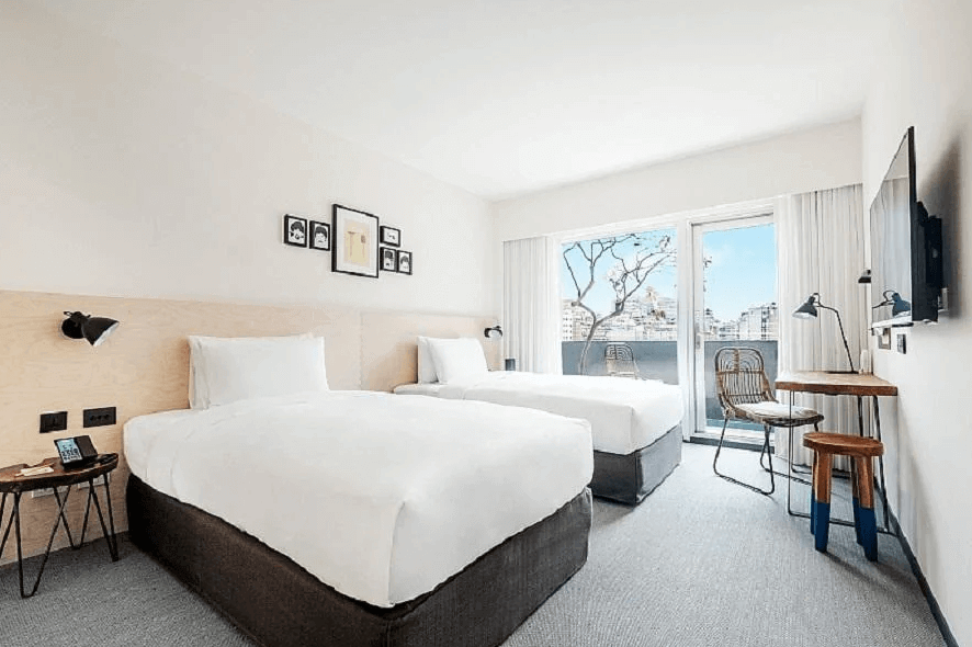 【寧夏夜市住宿】台北中山意舍酒店的兩張單人床客房，搭配現代化家具和簡約擺設，房間連接陽台，外景可以看到城市天際線，空間明亮且實用。