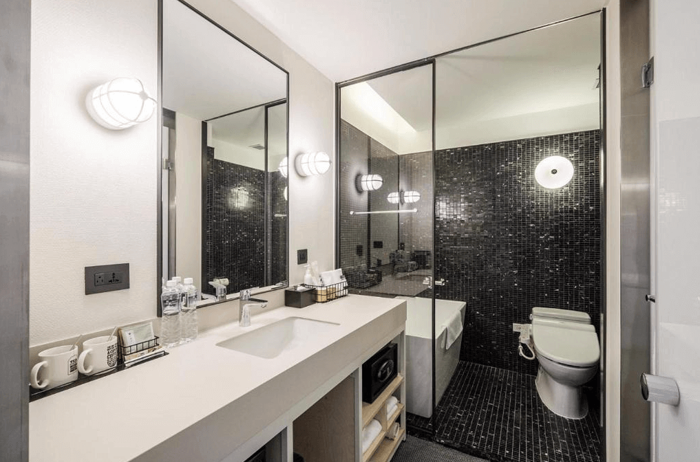 【寧夏夜市住宿】台北中山意舍酒店的浴室，採用黑色馬賽克瓷磚設計，配有寬敞的洗手台與鏡子，燈光柔和，空間整潔。