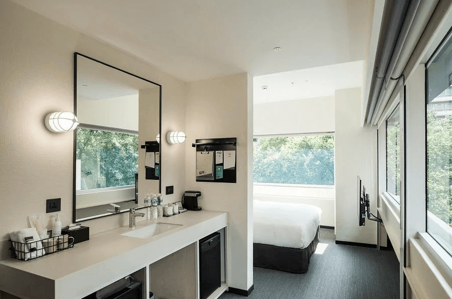 【寧夏夜市住宿】台北中山意舍酒店的房間內的開放式盥洗區，設有大型鏡子與洗手台，旁邊是大窗戶，可透進自然光線，整體設計簡潔且實用。