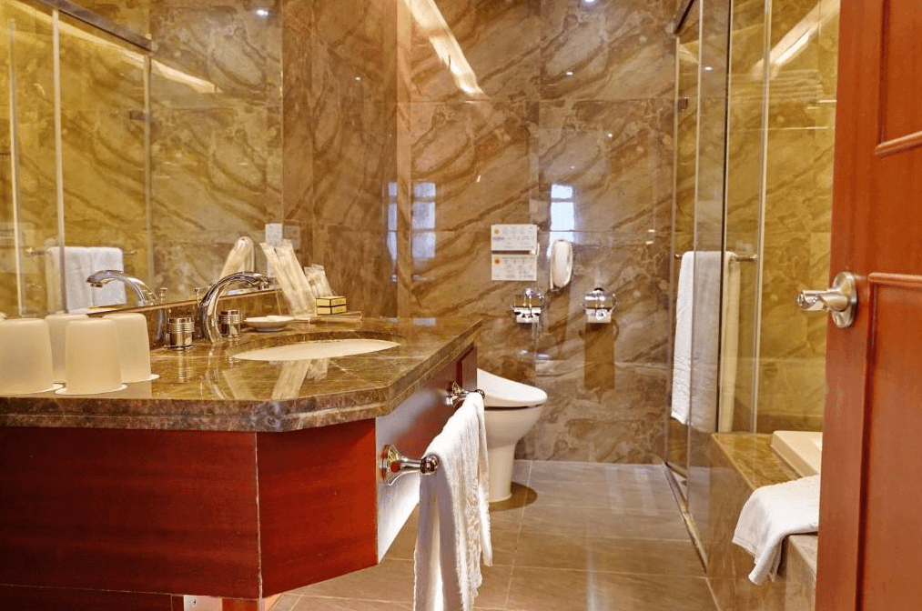 【寧夏夜市住宿】台北互舍酒店的浴室內以大理石材質為主設計，配有寬大的洗手台、馬桶和玻璃淋浴間，整體呈現高級而現代的質感。