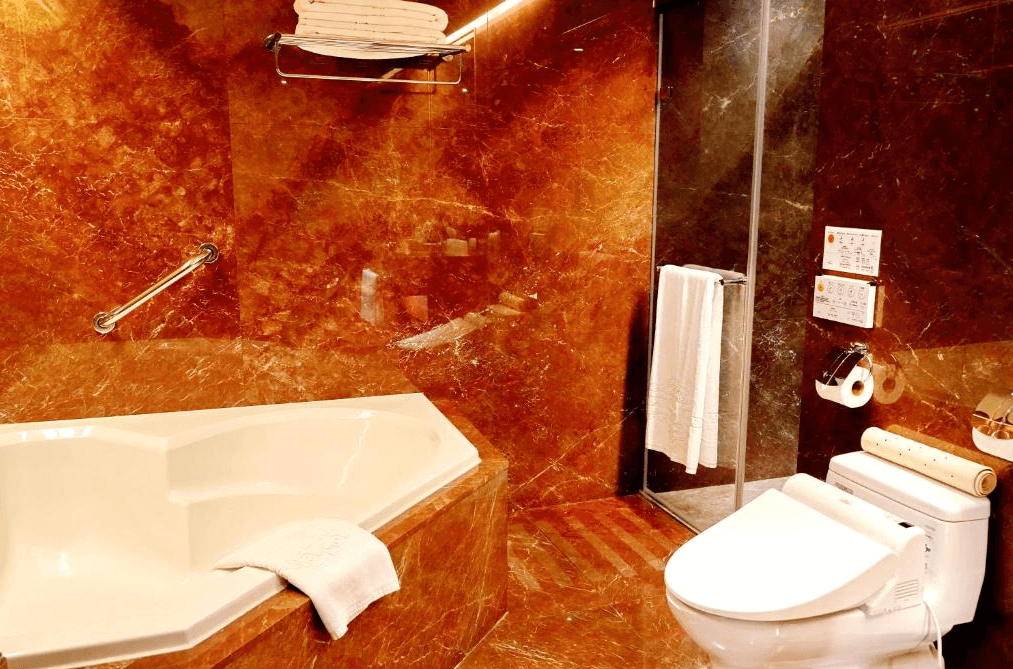 【寧夏夜市住宿】台北互舍酒店的浴室內設有豪華大理石浴缸和玻璃淋浴間，牆面以深色大理石覆蓋，營造出高雅奢華的氣氛。