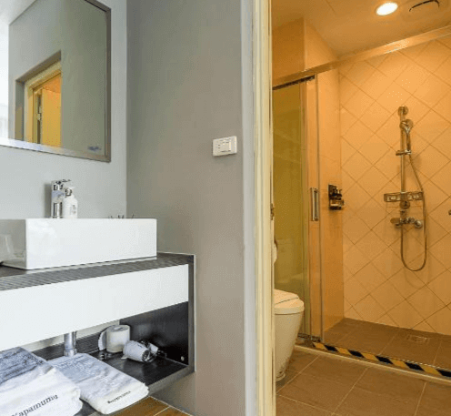 【日月潭住宿】嘎巴暮暮的浴室採用簡約現代風格，乾濕分離設計提升使用便利性。淋浴間以淺色系瓷磚鋪設，搭配明亮的洗手台與大鏡子，整體呈現乾淨整潔的視覺感受。