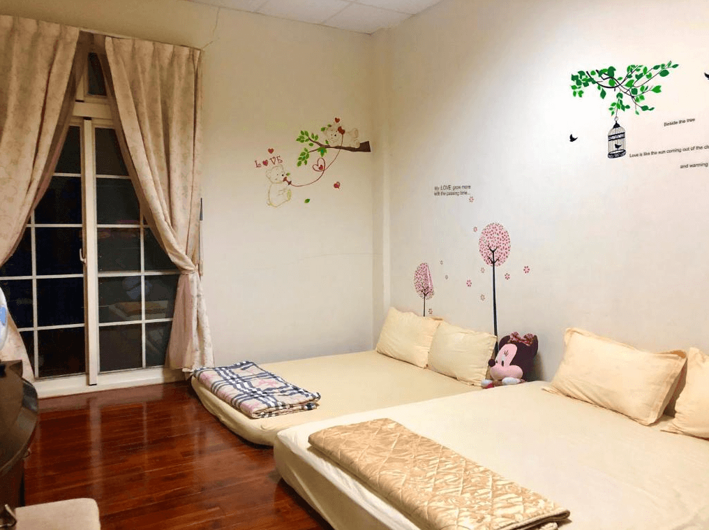 【嘉義寵物友善住宿】圓方居民宿溫暖色調的房間，牆面上裝飾著可愛的卡通樹和花朵圖案，房內設有兩張鋪有米黃色床墊的大床，窗邊搭配柔和的米色窗簾，整體氛圍舒適而親切。