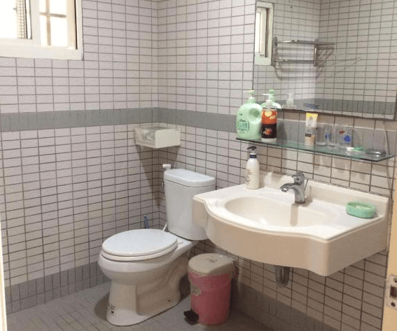 【嘉義寵物友善住宿】圓方居民宿的浴室，牆面與地板鋪有灰白色小方磚，配有洗手台、馬桶和鏡子，洗手台上擺放日常衛浴用品，整體設計簡潔實用。