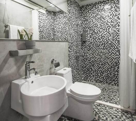 【寧夏夜市住宿】在家行旅-中山館的浴室，內部以灰色水泥牆面和黑白馬賽克瓷磚設計，配有簡約風格的洗手台、馬桶和淋浴間，整體乾淨明亮。