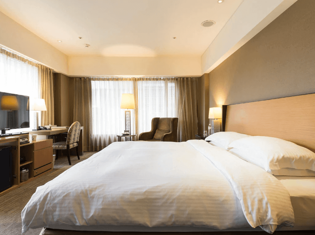 【寧夏夜市住宿】城市商旅-南西館的雙人房，配有大床，房間設計簡約典雅，光線充足，擺放著書桌、扶手椅與床頭燈，窗外可見城市景色，營造舒適居住氛圍。