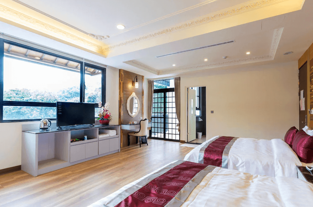 【埔里住宿】埔里夏都華蔓山林渡假會館的雙床房，配有兩張舒適的大床，房間內設有窗戶可欣賞外部景觀，並提供基本的居家設施如電視、電熱水壺和簡單的化妝桌，適合家庭或朋友入住。