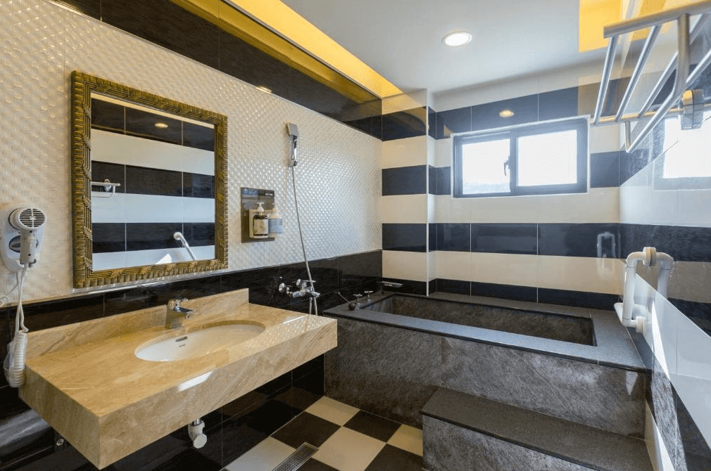 【埔里住宿】埔里夏都華蔓山林渡假會館的浴室空間，牆面以大理石紋路及黑白條紋設計，配有浴缸及乾濕分離淋浴區，提供高品質的洗浴體驗。