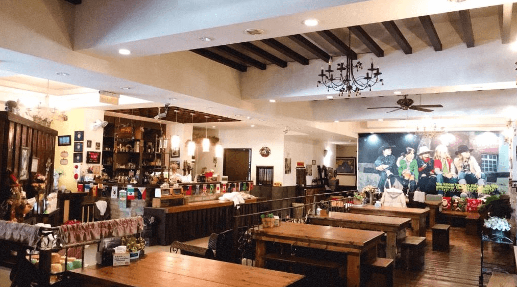 【埔里住宿】埔里小鎮歐式民宿與背包客棧的公共空間寬敞明亮，挑高天花板設有吊燈，裝潢融合了歐式鄉村風與現代簡約感。室內擺放長木桌和木椅，適合旅人聚會或享用餐點，充滿溫馨社交氛圍。