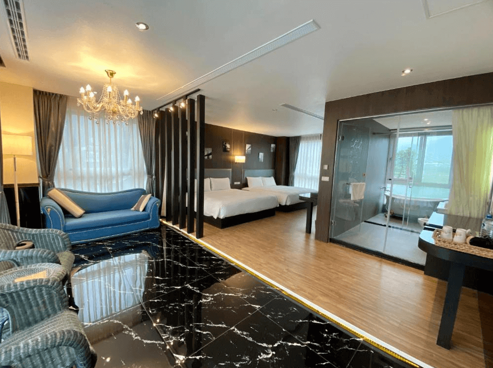 【埔里住宿】埔里日記的豪華客房內設有雙床區域和玻璃淋浴間，房內以深色木質裝潢為主，搭配藍色沙發和大理石地板，展現現代與奢華的氛圍。