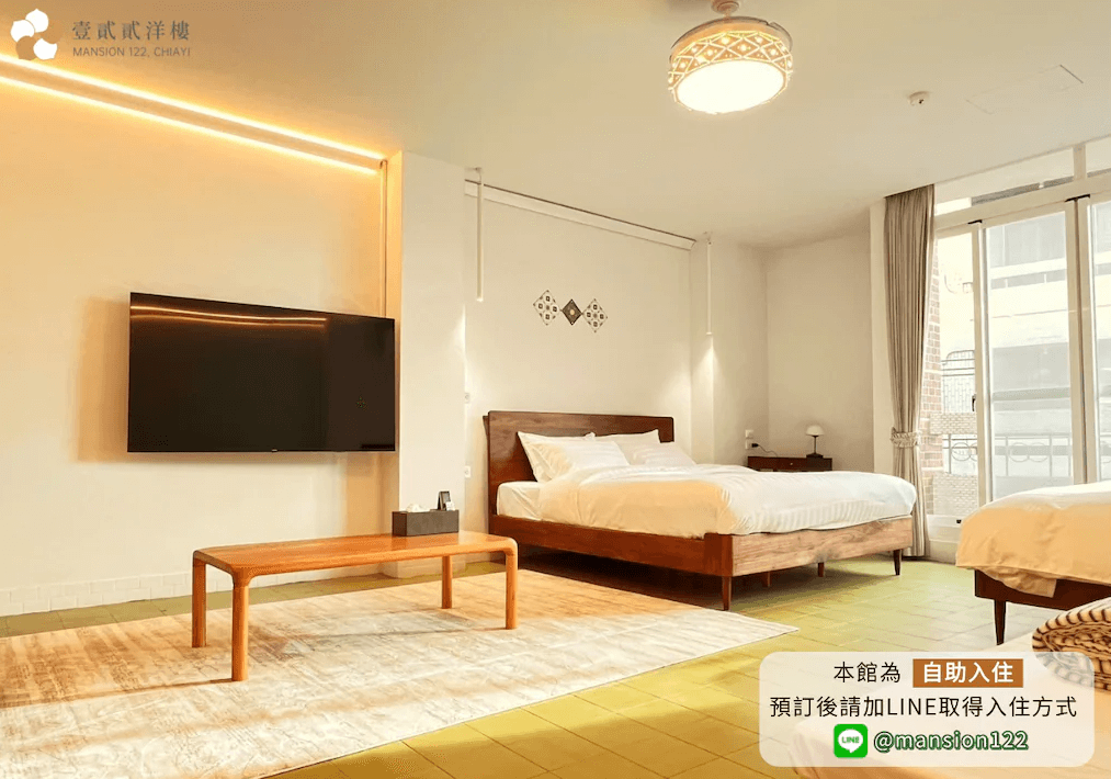 【嘉義寵物友善住宿】壹貳貳洋樓的客房，配有兩張雙人床，牆上安裝了一台大型平面電視，房間內設有簡約木製家具，靠窗位置有自然光透入，營造舒適溫馨的氛圍。