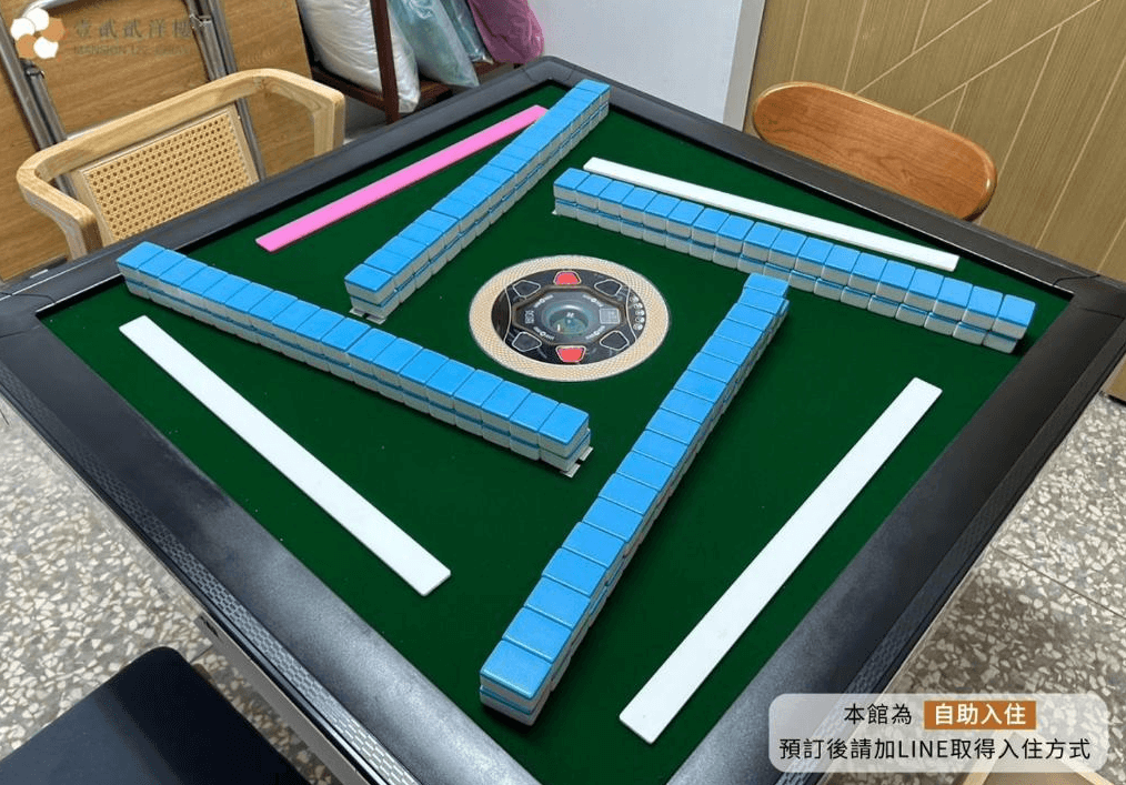【嘉義寵物友善住宿】壹貳貳洋樓的自動麻將桌，上面排列著藍色麻將牌，桌子周圍有幾張木椅，空間設計適合娛樂活動。