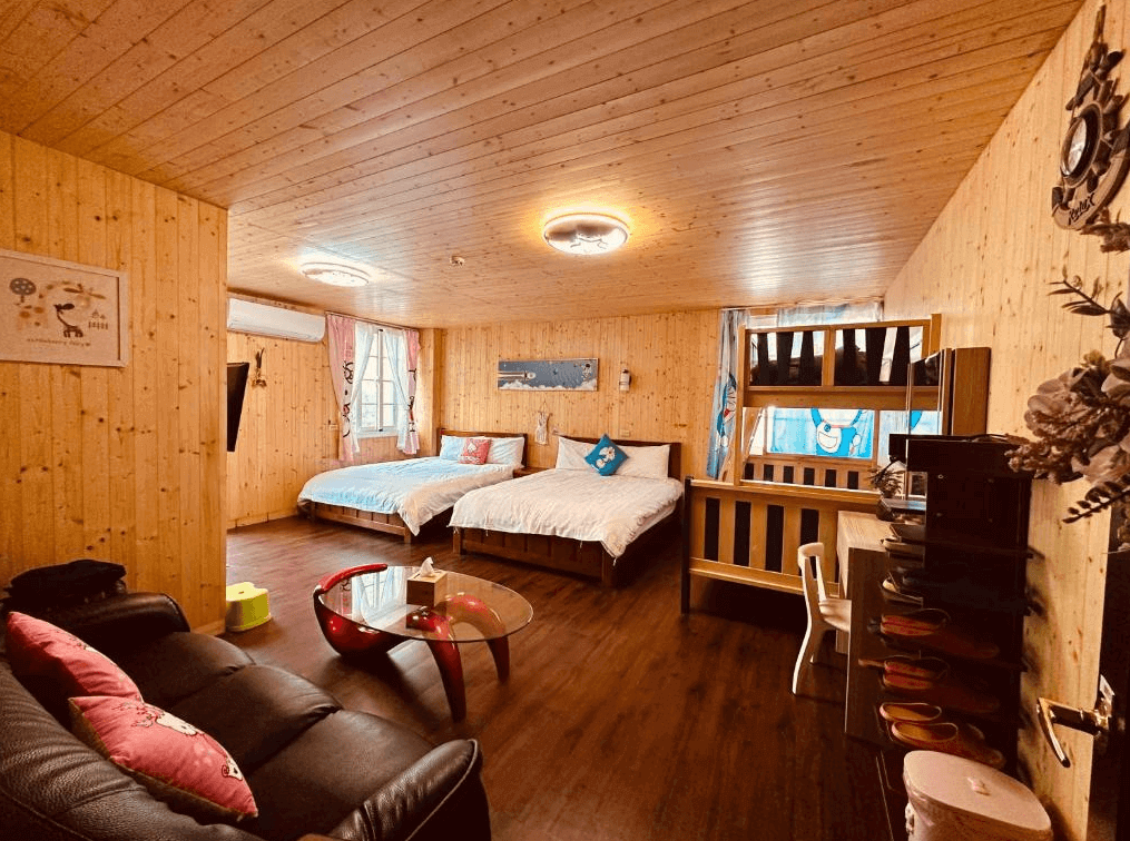 【阿里山住宿】大方茶業民宿的房間以全木質裝潢打造，溫暖而舒適，內有雙人床與上下舖設計，適合家庭或多人入住。房間內配有沙發與簡單的家具，增添實用性和舒適感。