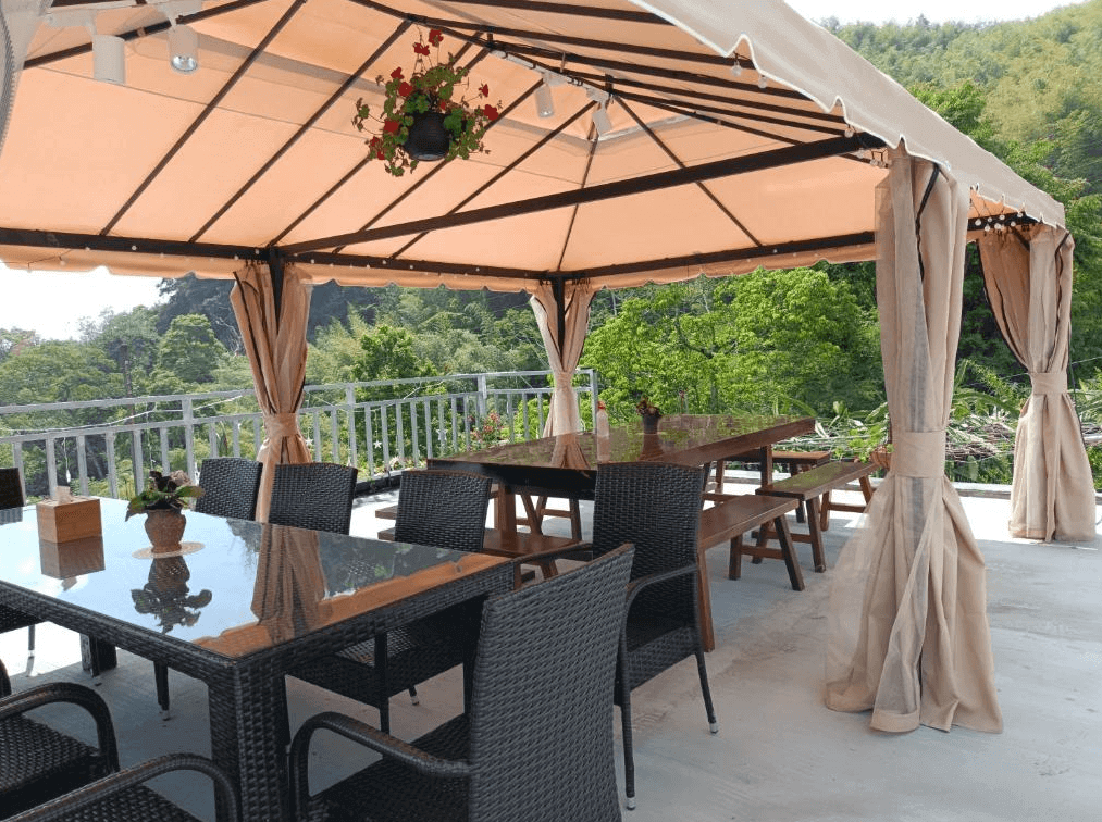 【阿里山住宿】大方茶業民宿設有遮陽棚的戶外用餐區，配備長桌與藤椅，能欣賞周邊的山景與自然風光，非常適合家庭或朋友聚會。