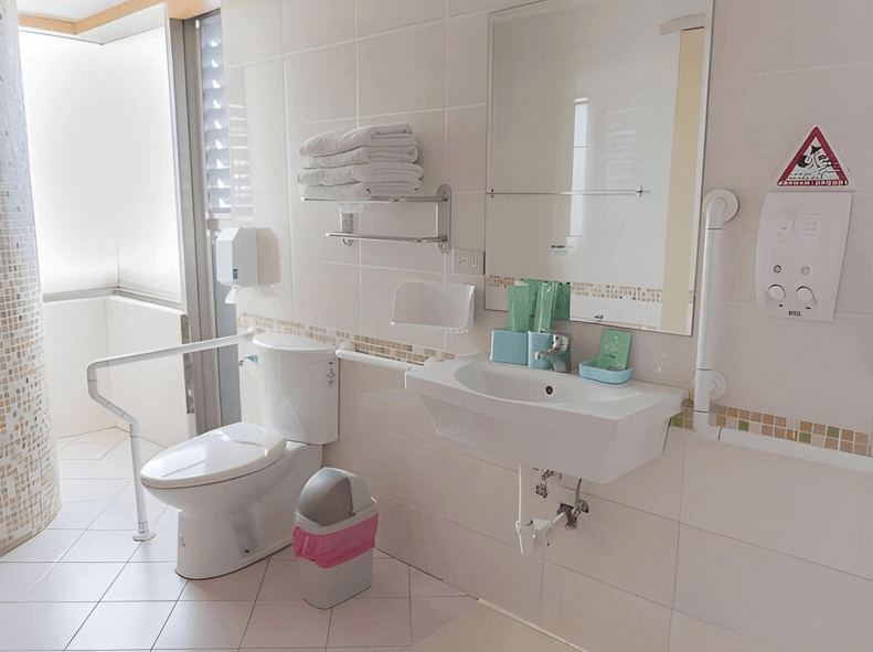 【嘉義寵物友善住宿】安蘭居旅店的浴室，採用白色設計，配有無障礙設施如扶手，裝備齊全，包括洗手台、馬桶和淋浴間，空間乾淨整潔。