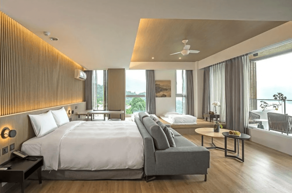 【日月潭住宿】承億文旅 潭日月的豪華套房內裝簡潔大方，窗外景色盡收眼底。房內設有榻榻米區，提供多功能的休憩空間，搭配灰色沙發與木質傢俱，呈現舒適且時尚的住宿體驗。