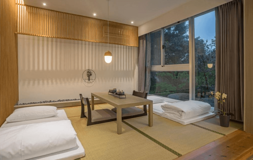 【日月潭住宿】承億文旅 潭日月的榻榻米房型設計靜謐且充滿日式禪意，牆面木條裝飾與柔和燈光相映成趣。大片窗戶讓住客享受自然景觀，低矮的桌椅設計突顯簡約美感，適合靜心放鬆。