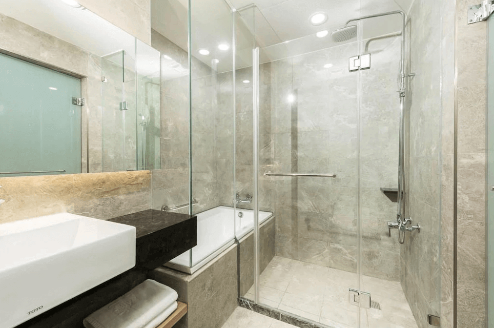 【新竹火車站住宿】新苑庭園大飯店的浴室內設有乾濕分離的淋浴間與浴缸，牆面與地板使用大理石紋理設計，展現高級感。洗手台採用白色設計，搭配大面積鏡子，提供明亮的空間感。