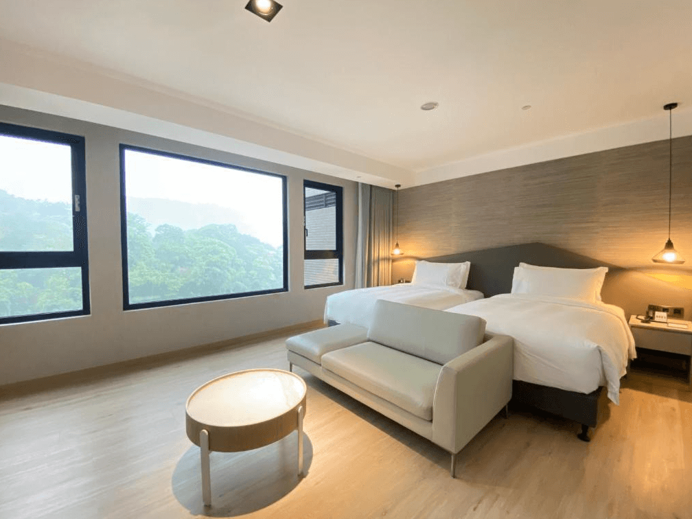 【日月潭住宿】日月潭力麗溫德姆溫泉酒店簡約現代的房間，內部採用大面積落地窗設計，窗外是一片茂密的綠色森林景觀，為住客提供清新而寧靜的氛圍。