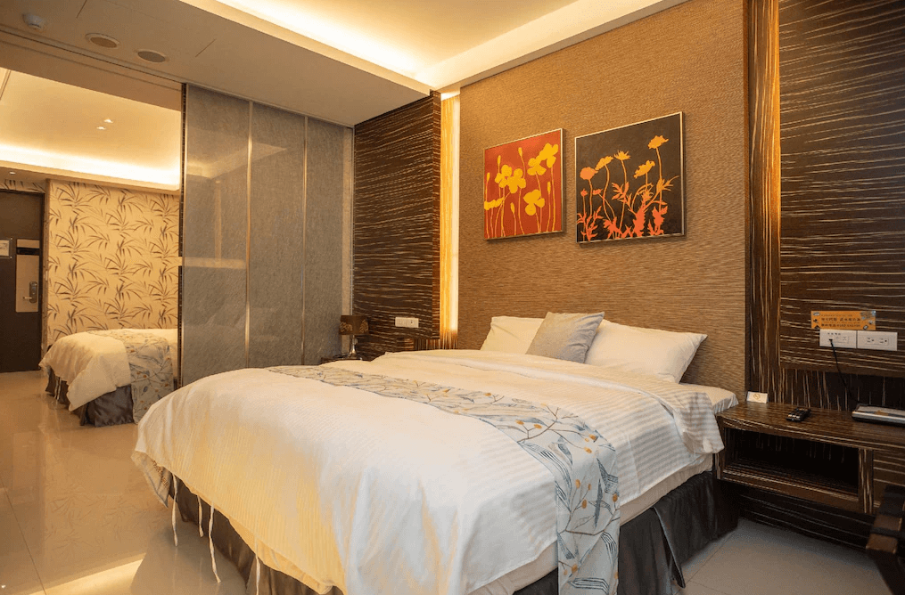 【日月潭住宿】日月潭天月水色民宿的房間設計以高雅溫暖為主調，床頭背景牆採用木紋質感搭配簡約繪畫，營造出自然舒適的氛圍。室內使用柔和燈光增添溫馨感，兩張雙人床適合家庭或團體入住。