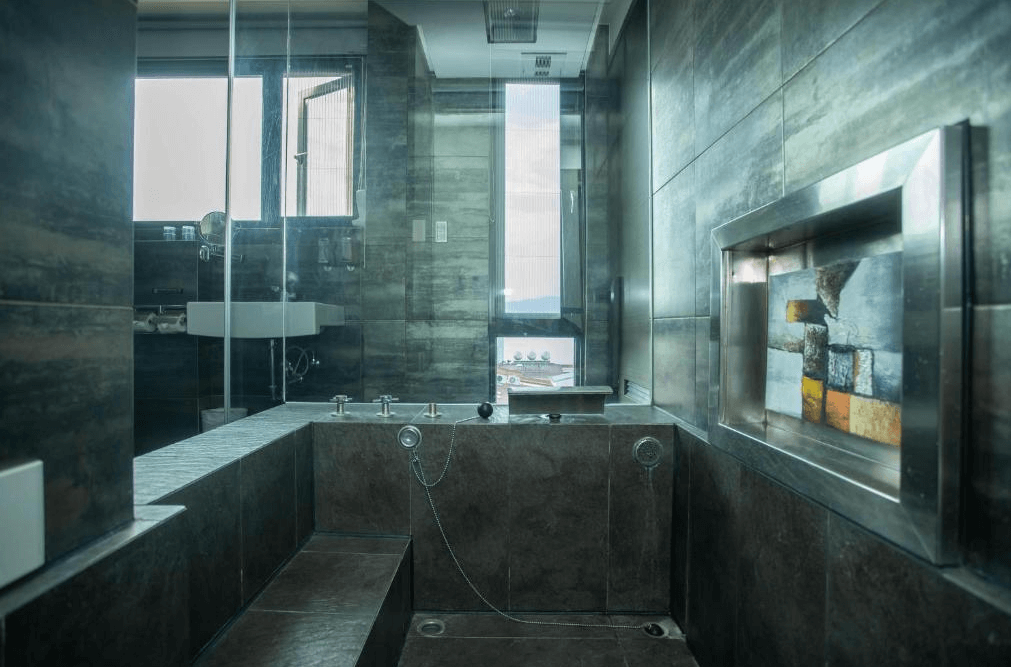 【日月潭住宿】日月潭天月水色民宿的浴室採用深色系瓷磚設計，展現穩重大方的風格。內設按摩浴缸，窗外景觀優美，讓住客在沐浴時也能欣賞美麗湖景，提供放鬆的享受。