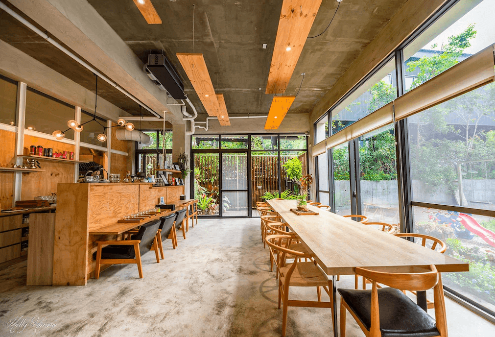 【日月潭住宿】日月潭山慕藝旅的餐廳空間以現代工業風格為主，木質桌椅搭配大量玻璃窗，讓室內明亮且與戶外景色相呼應。設計細緻的燈飾與植物點綴，使用餐環境充滿溫馨與自然氣息。