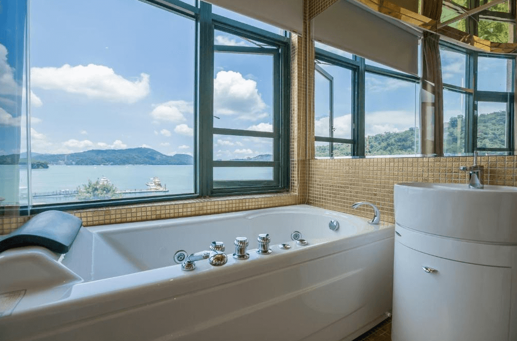 【日月潭住宿】日月潭水岸休閒飯店配有按摩浴缸的浴室，窗外可以欣賞湖景，牆面以金色馬賽克裝飾，展現精緻與奢華。