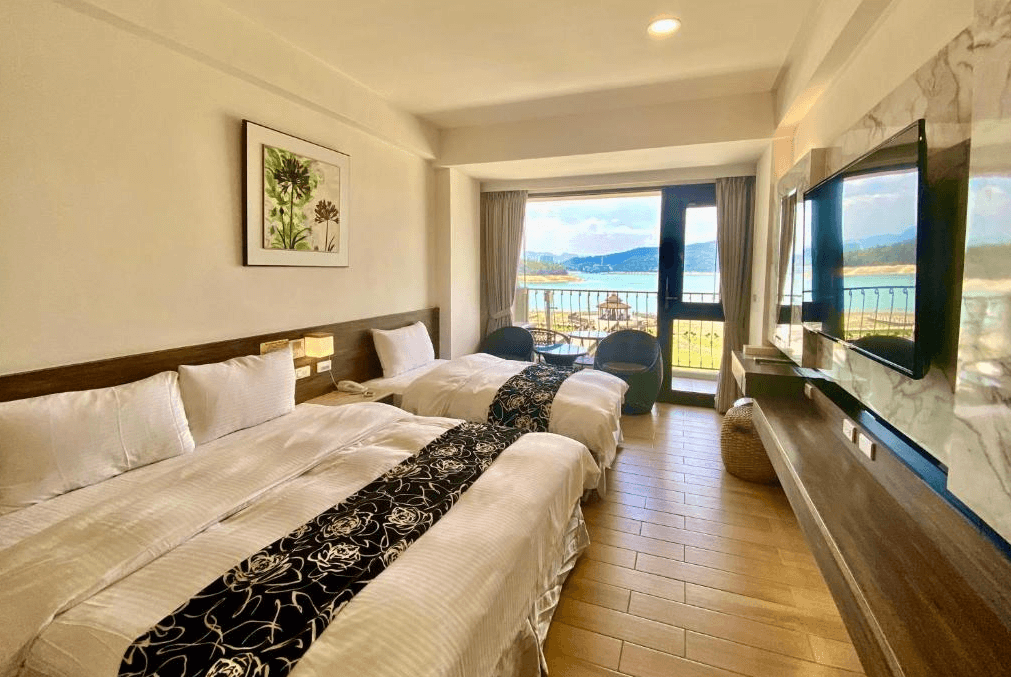 【日月潭住宿】明月湖品味湖畔旅店的湖景雙人房設計簡約溫馨，寢具搭配優雅的花紋床尾巾增添質感。房內設有陽台與座椅，住客可近距離欣賞湖光山色，體驗舒適放鬆的住宿氛圍。