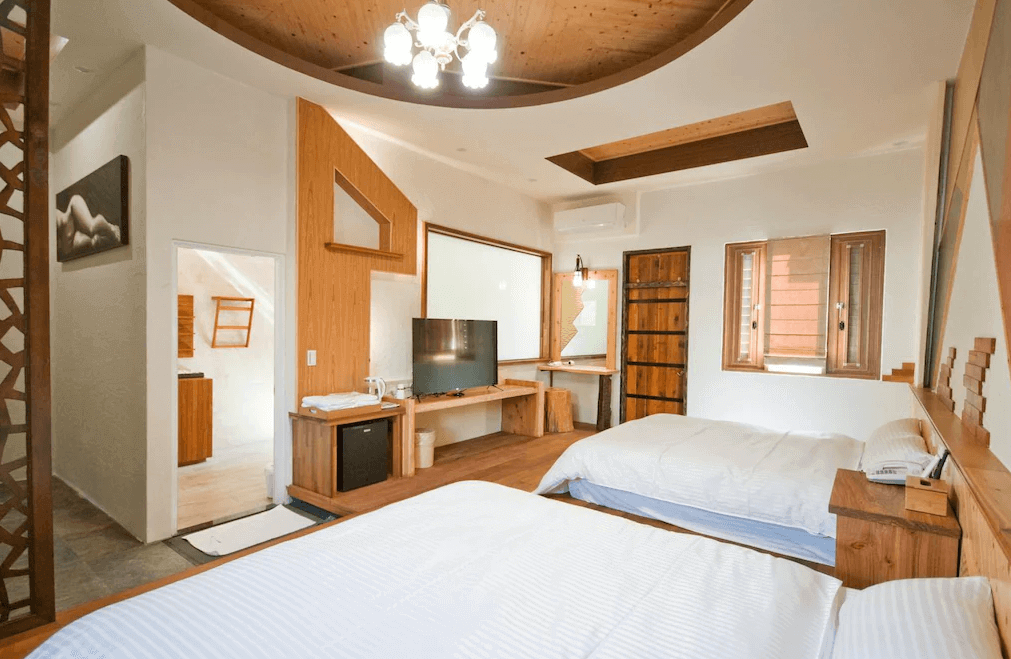 【廬山溫泉】春陽一品居雙人床的寬敞房間，結合傳統木質元素與現代設計感，擁有電視、化妝桌與獨立衛浴。房間內部裝潢以木紋與幾何設計為特色，搭配溫暖燈光，呈現溫馨舒適的氛圍。