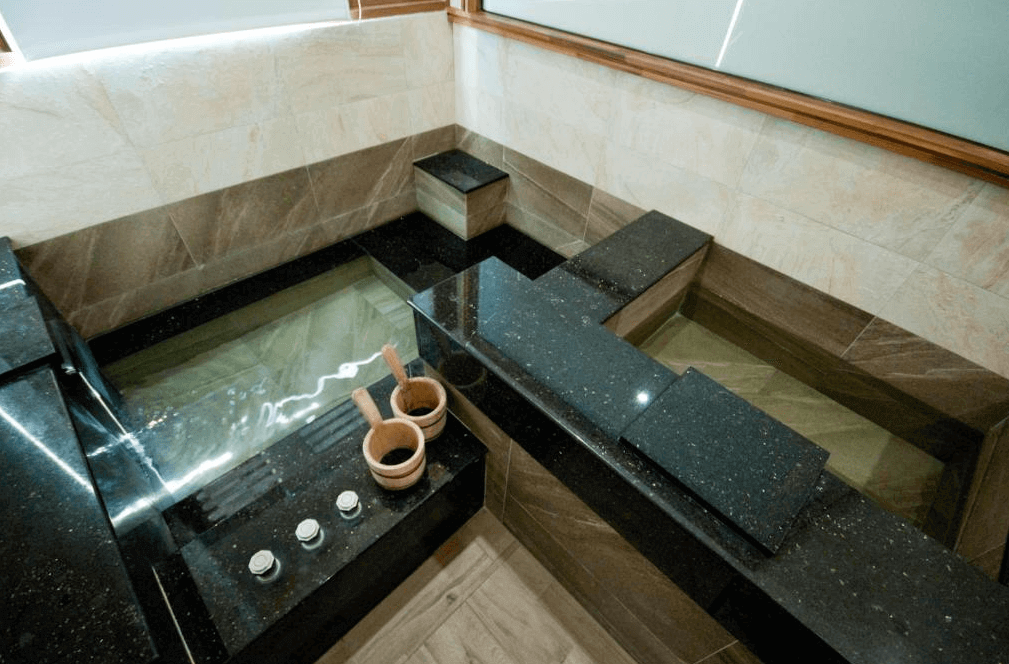 【廬山溫泉】春陽一品居的房內私人溫泉泡湯池，採用黑色大理石設計，搭配木質湯勺，提供放鬆身心的溫泉體驗。浴池旁設有調溫旋鈕，可自行調整水溫，整體空間典雅且具有隱私感。